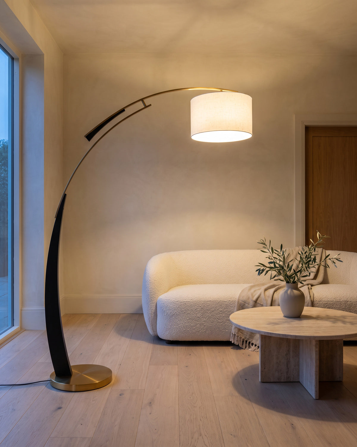 Lampadaire Arpège (arc noir et doré, tambour) dans une pièce, allumé en soirée