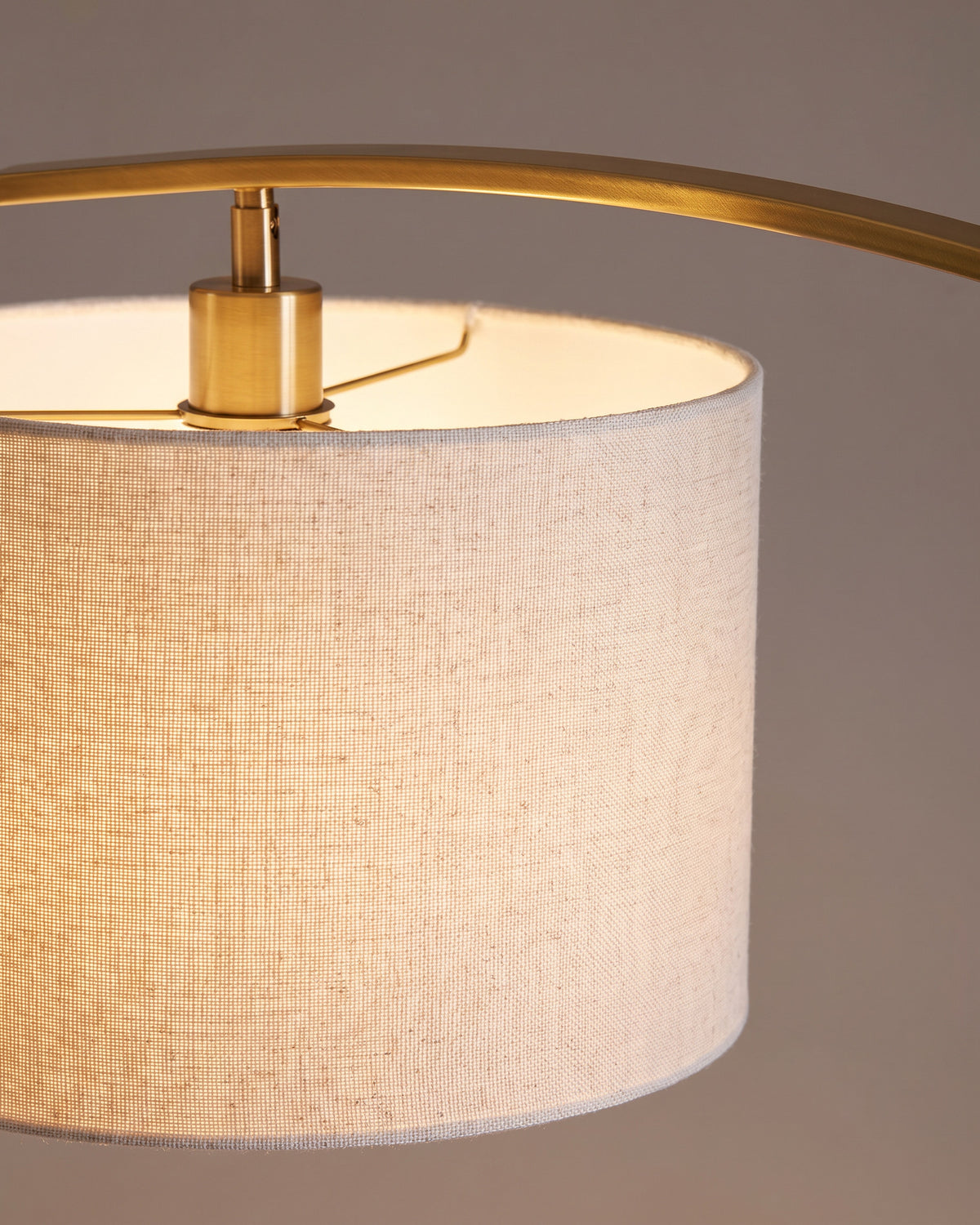 Lampadaire Arpège : gros plan sur la matière (arc noir et doré, socle doré, abat-jour tambour en tissu clair)