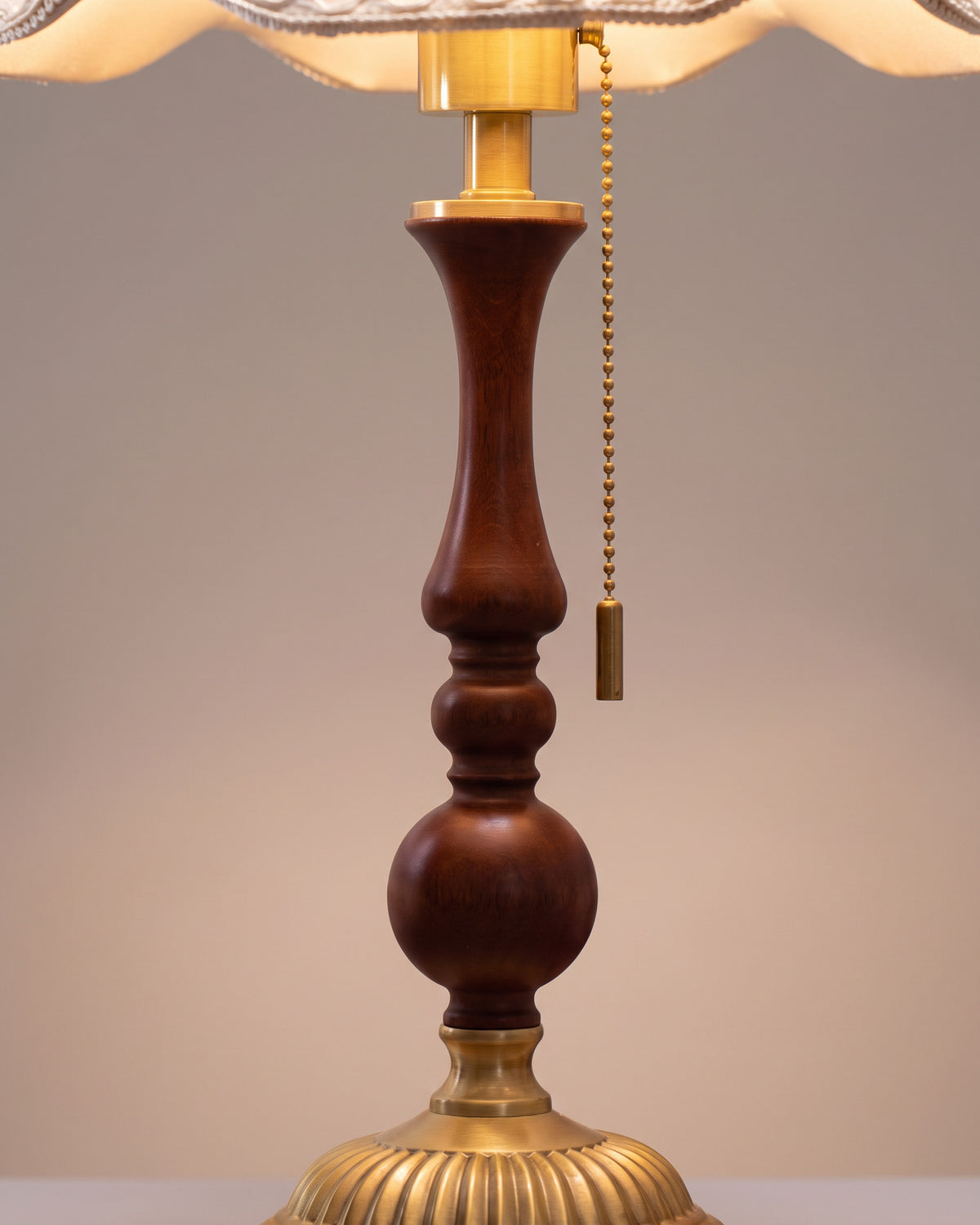 Lampe de table Balustre : gros plan sur le bord festonné de l'abat-jour en lin et le haut du fût tourné en noyer