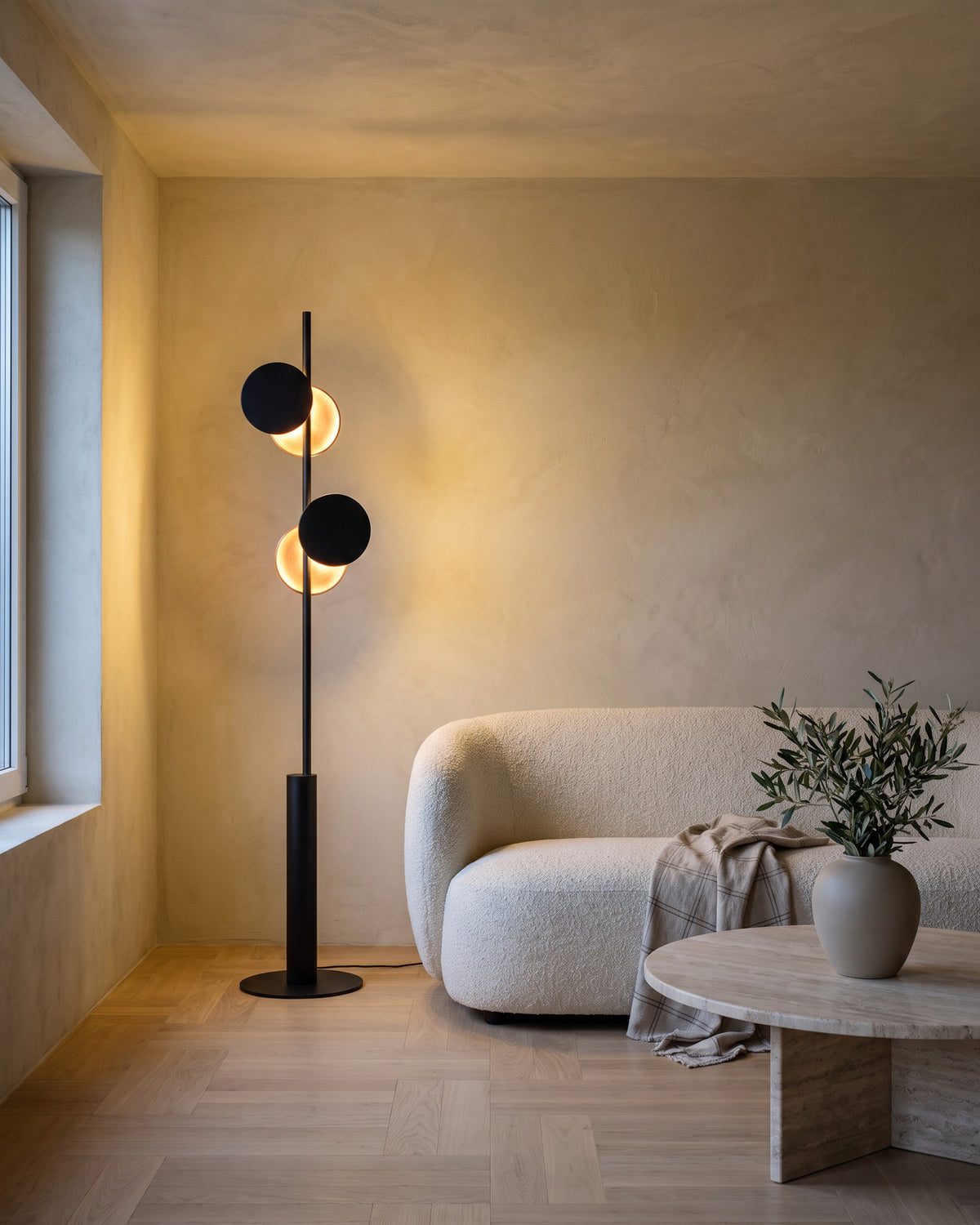 Lampadaire Phases (disques noirs, envers cuivré) dans une pièce, allumé en soirée