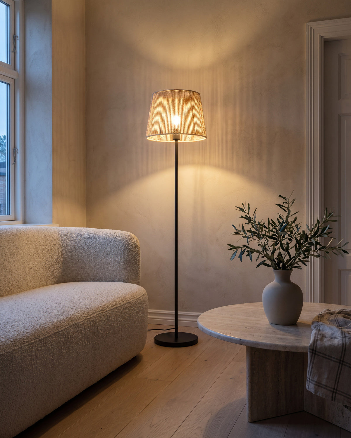 Lampadaire Raphia (corde tressée et pied noir) dans une pièce, allumé en soirée