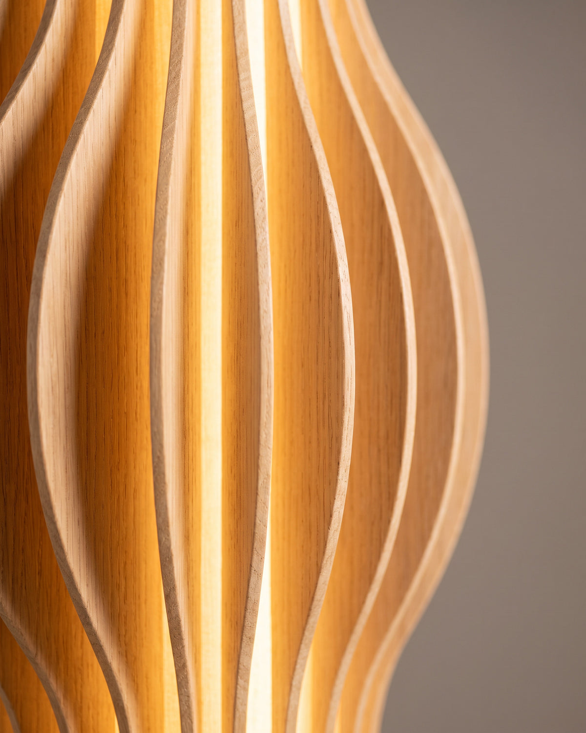 Lampadaire Torsade : gros plan sur les lamelles de bois clair torsadées au niveau du pincement central, éclairées de l'intérieur