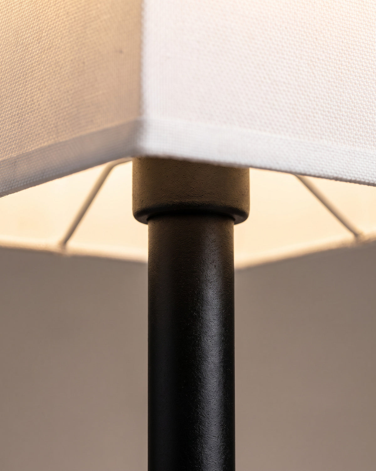 Lampe de table Pilastre : gros plan sur l'abat-jour carré en tissu blanc lumineux et sa jonction avec la tige noire