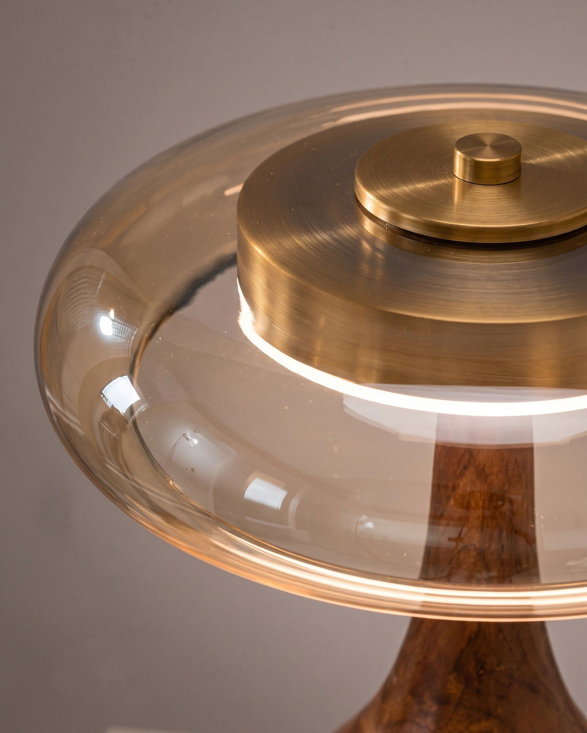 Lampe de table Mirabelle : gros plan sur le bord du disque en verre ambré et le capuchon doré