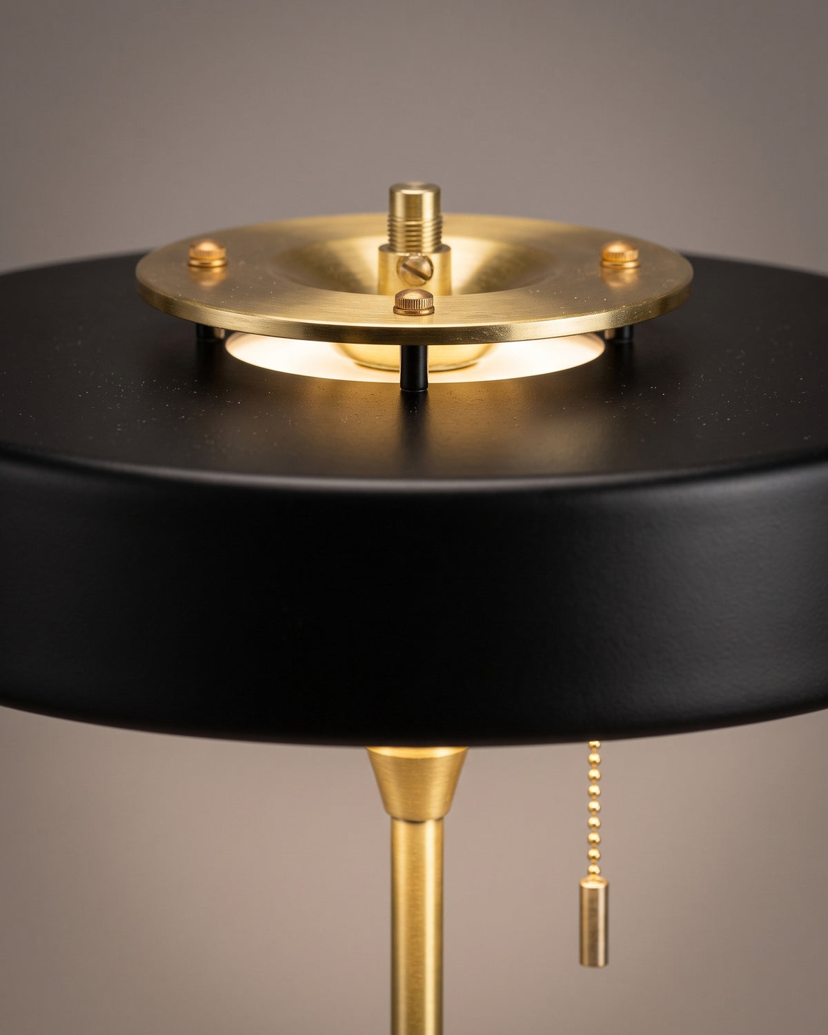 Lampe de table Médaillon: gros plan sur le dessus du disque laqué avec son anneau doré et le haut de la tige