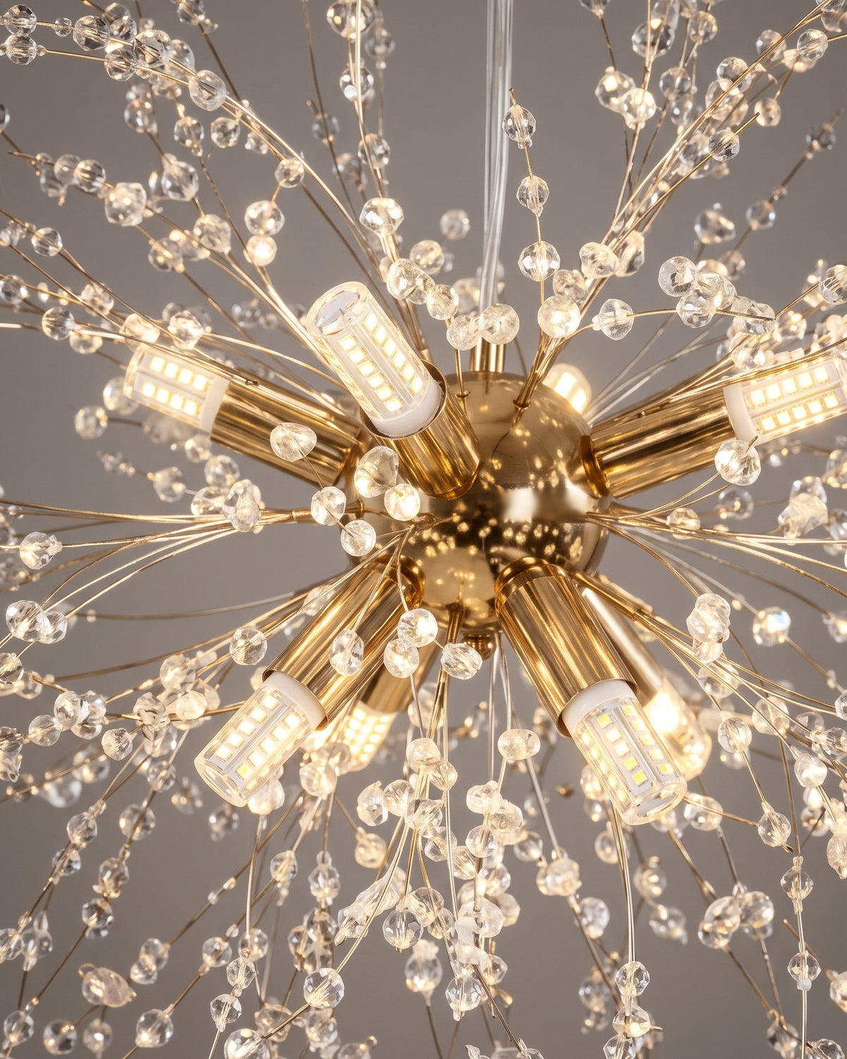 Lustre Aigrette : gros plan sur les tiges dorées rayonnantes et leurs perles de verre près du cœur lumineux