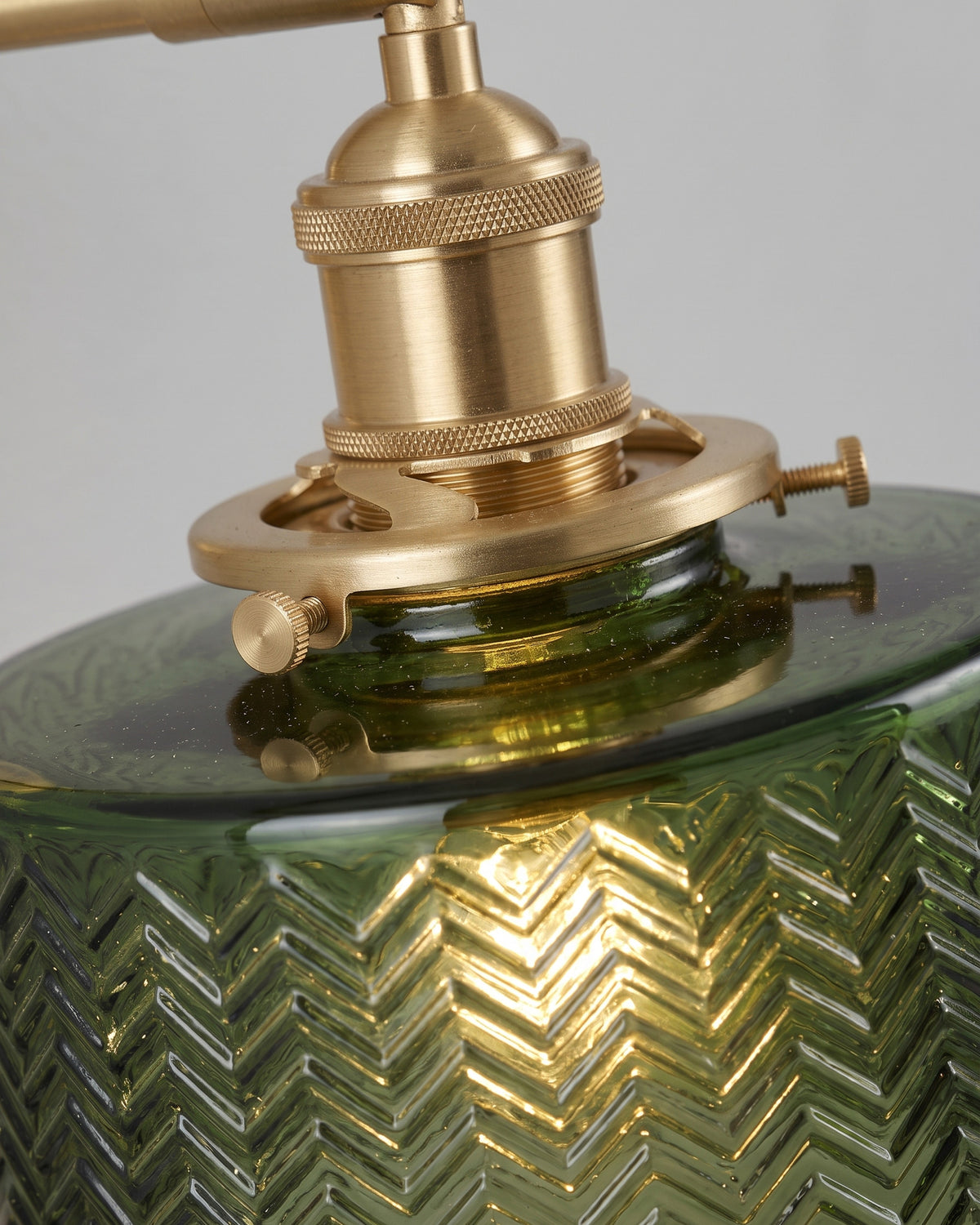 Applique Chevron: gros plan sur la douille dorée moletée à vis et le haut du verre ciselé