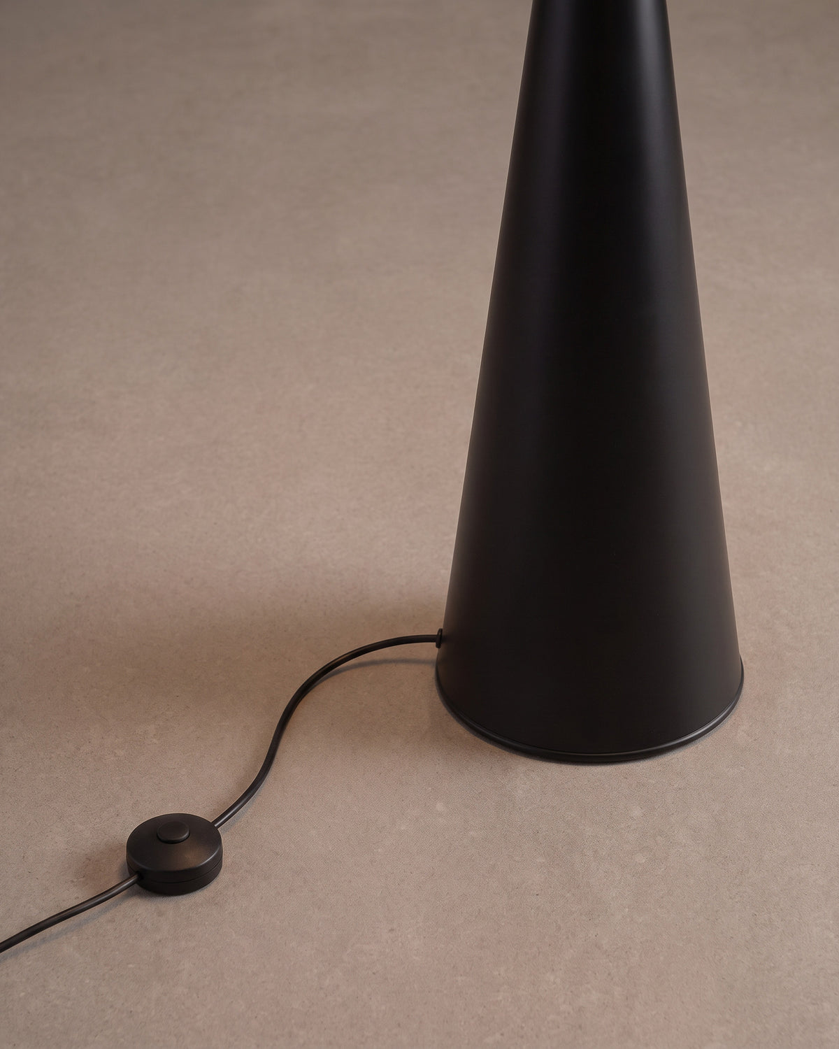 Lampadaire Cône : détail, la base du cône posée au sol et l'interrupteur au pied sur le câble