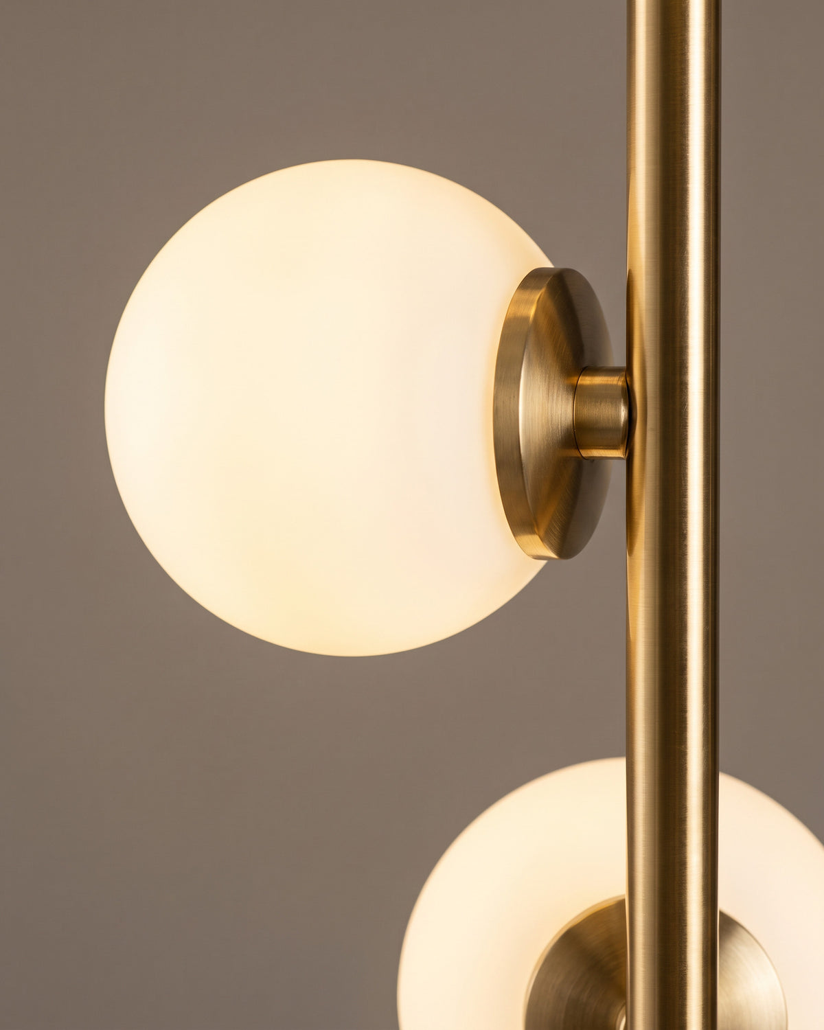 Lampadaire Perles : gros plan sur un globe opalin blanc fixé à la tige dorée par sa petite platine ronde