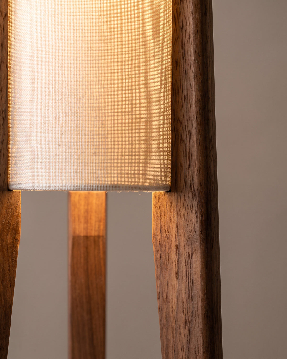 Lampadaire Menhir : gros plan sur la matière (trépied en bois de teinte noyer, colonne en tissu clair)