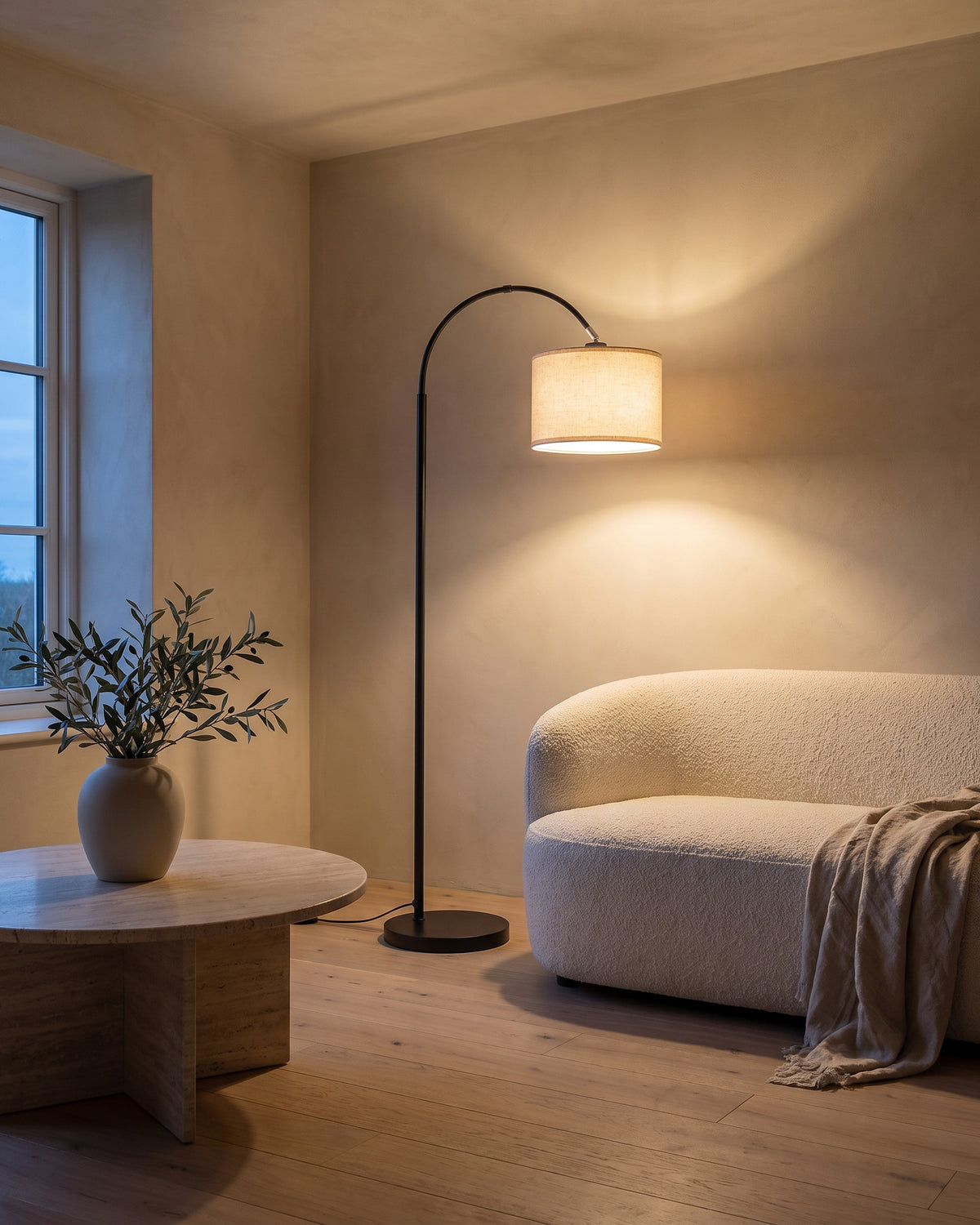 Lampadaire Crosse (arc noir et abat-jour en tissu) dans une pièce, allumé en soirée