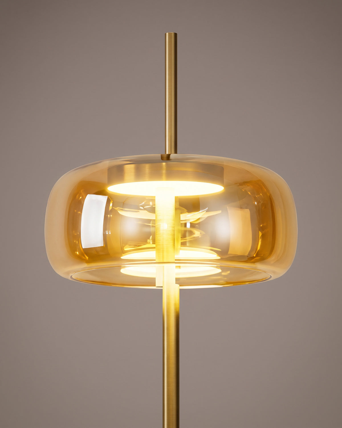 Lampadaire Cabochon : gros plan sur le dôme en verre ambré et sa fixation dorée au sommet de la tige
