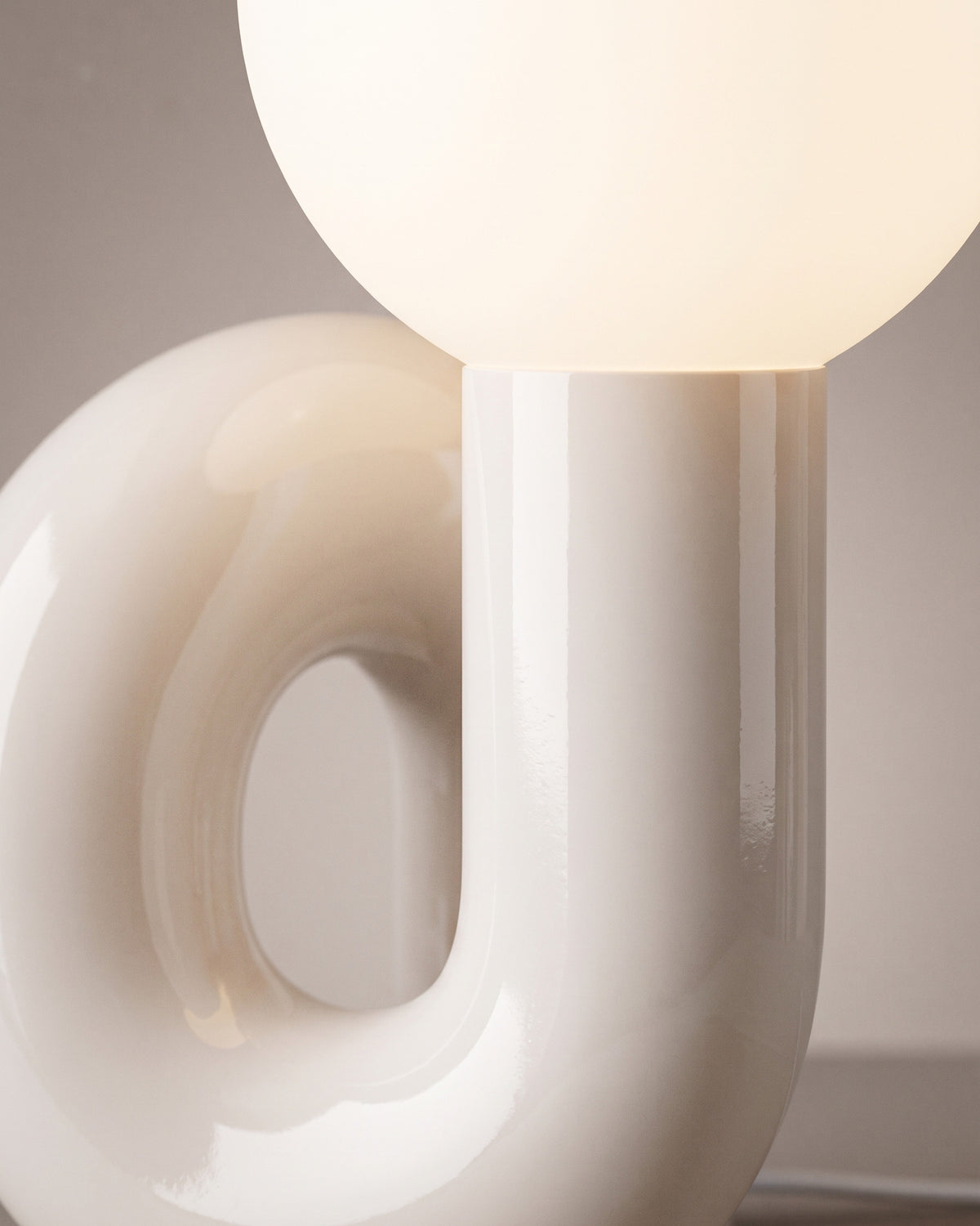 Lampe de table Volute: gros plan sur la courbe brillante du tube et la base du globe opalin