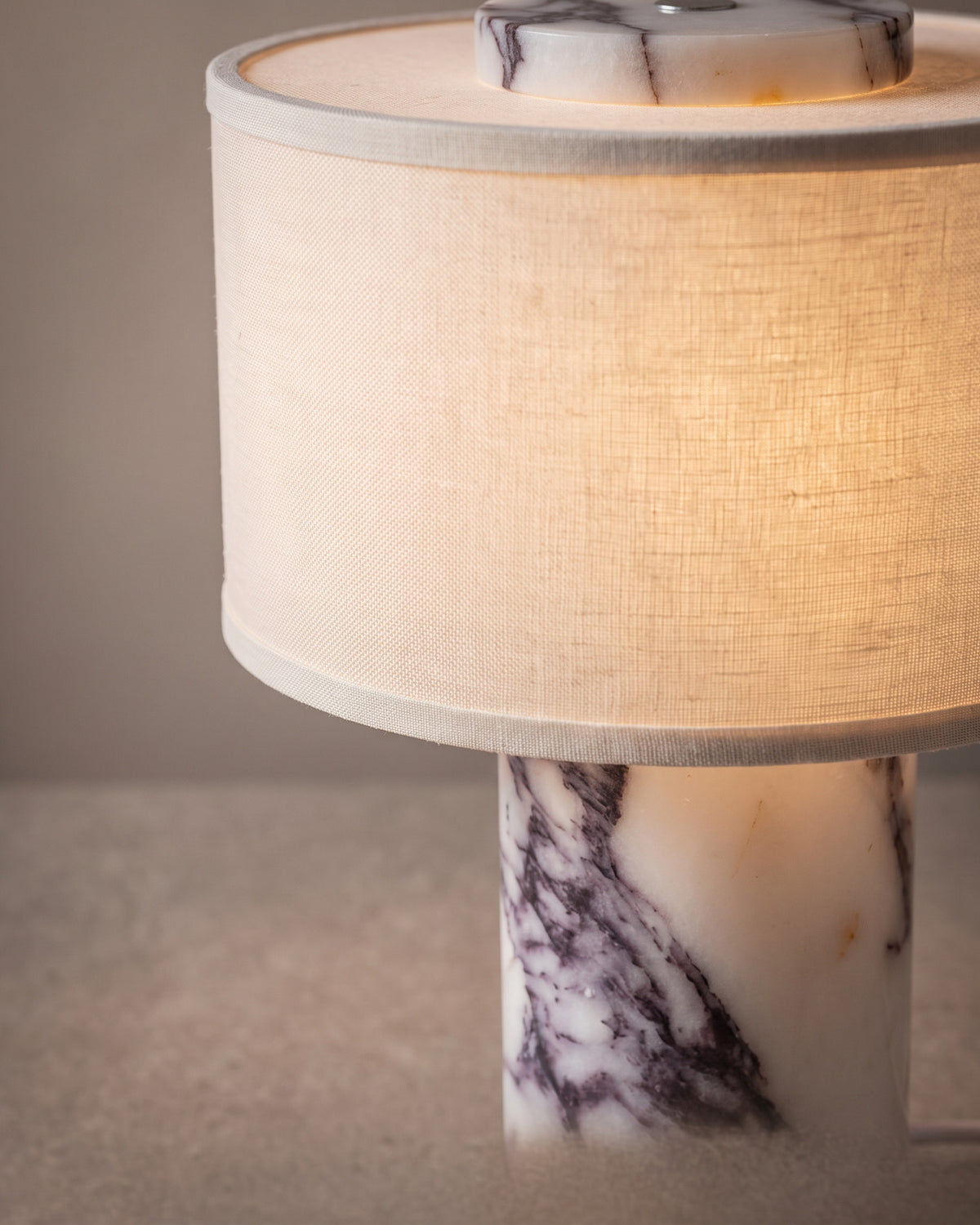 Lampe de table Améthyste: gros plan sur le veinage violet et gris du pied cylindrique en marbre