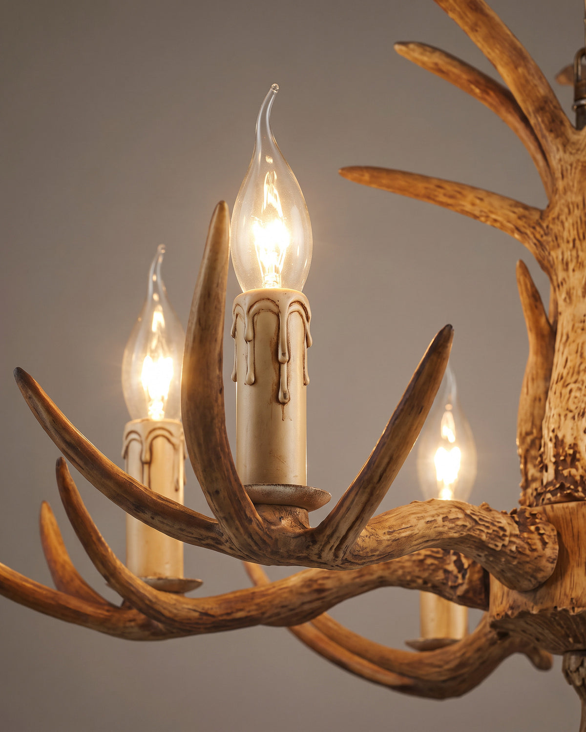Lustre Ramure : gros plan sur les ramures sculptées et deux fausses bougies avec coulures de cire