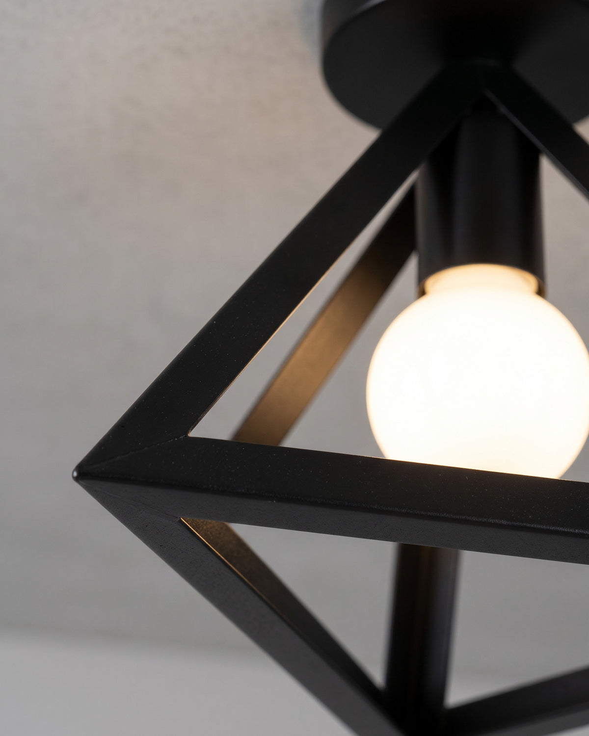 Plafonnier Origami: gros plan sur un angle de la cage en lamelles noires avec l'ampoule globe au centre