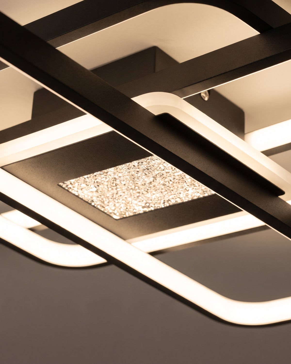 Plafonnier Entrelacs : gros plan sur l'angle arrondi d'un cadre noir avec sa bande lumineuse et le panneau central effet verre