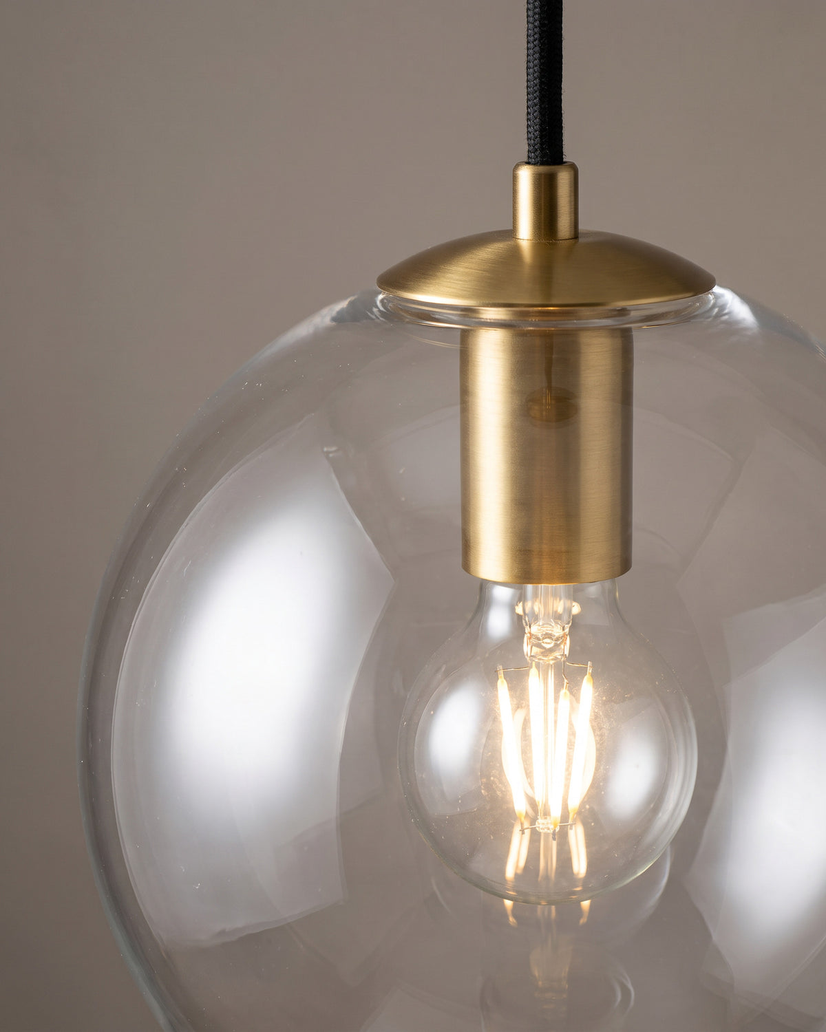 Suspension Bocal : gros plan sur le col du globe avec la bague dorée et l'ampoule au centre du verre