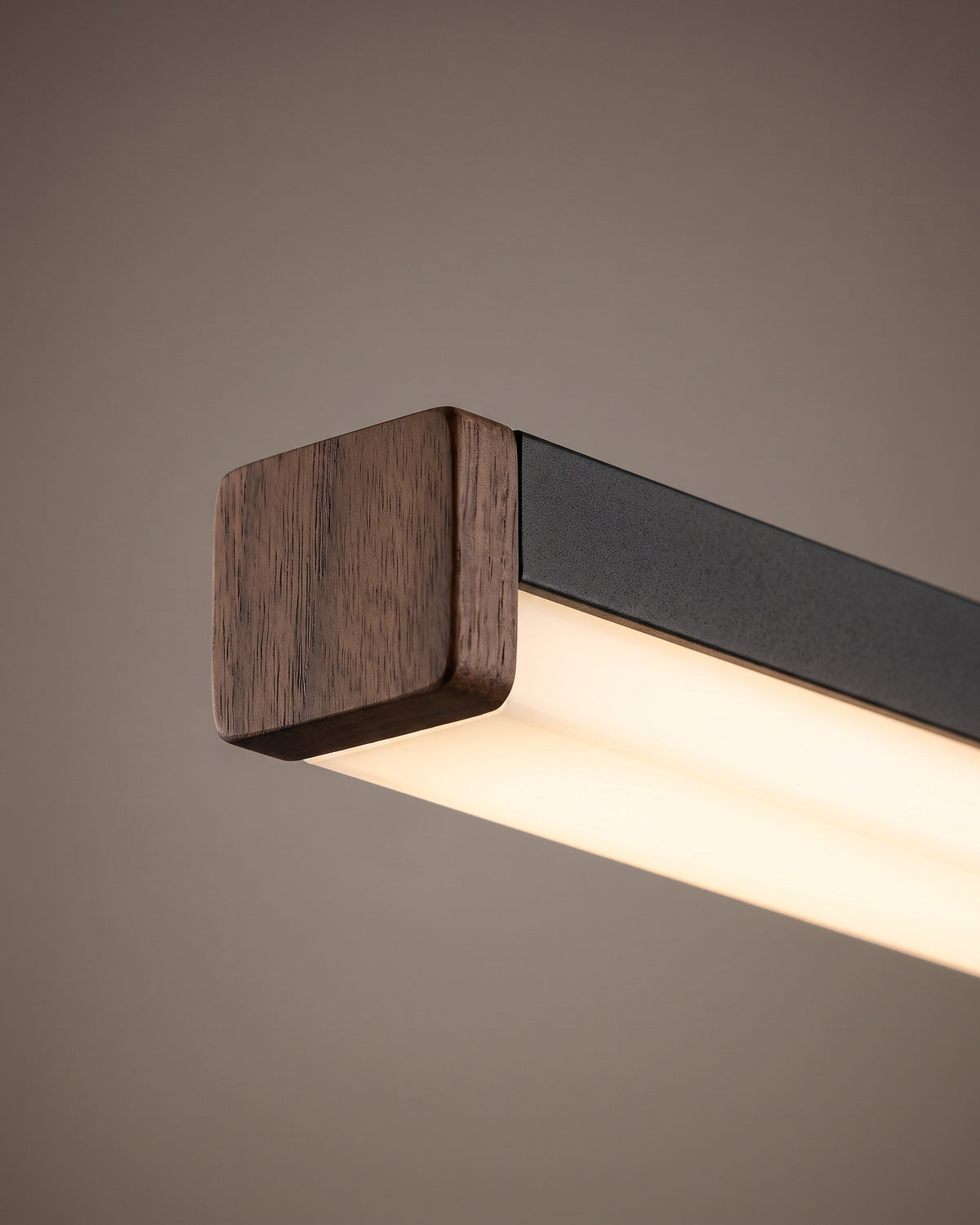 Suspension Baguette: gros plan sur l'embout en bois foncé à l'extrémité du profilé noir et le diffuseur lumineux