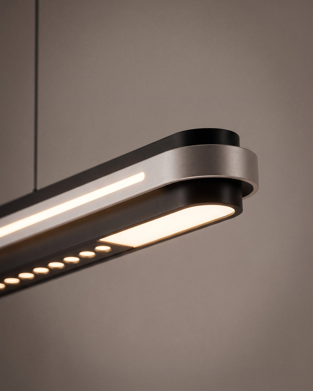 Suspension Graphite : gros plan sur la rangée de petits spots ronds encastrés sous la barre et la ligne lumineuse supérieure