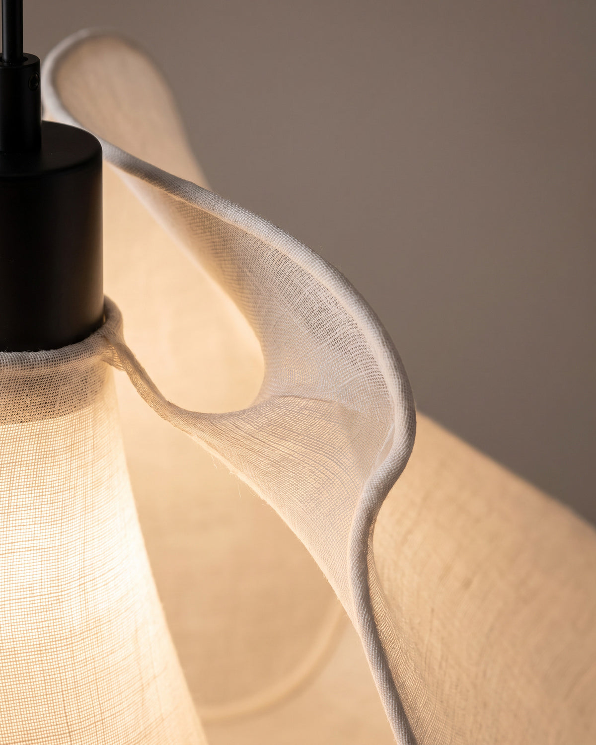 Suspension Soie : gros plan sur le pli d'une volute de tissu traversée par la lumière