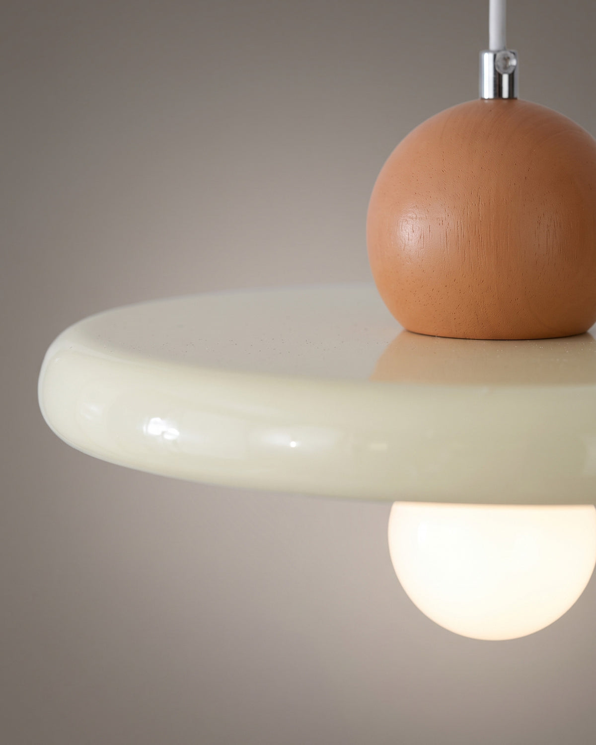 Suspension Écuelle: gros plan sur le capuchon chromé et la courbe brillante de la soucoupe laquée