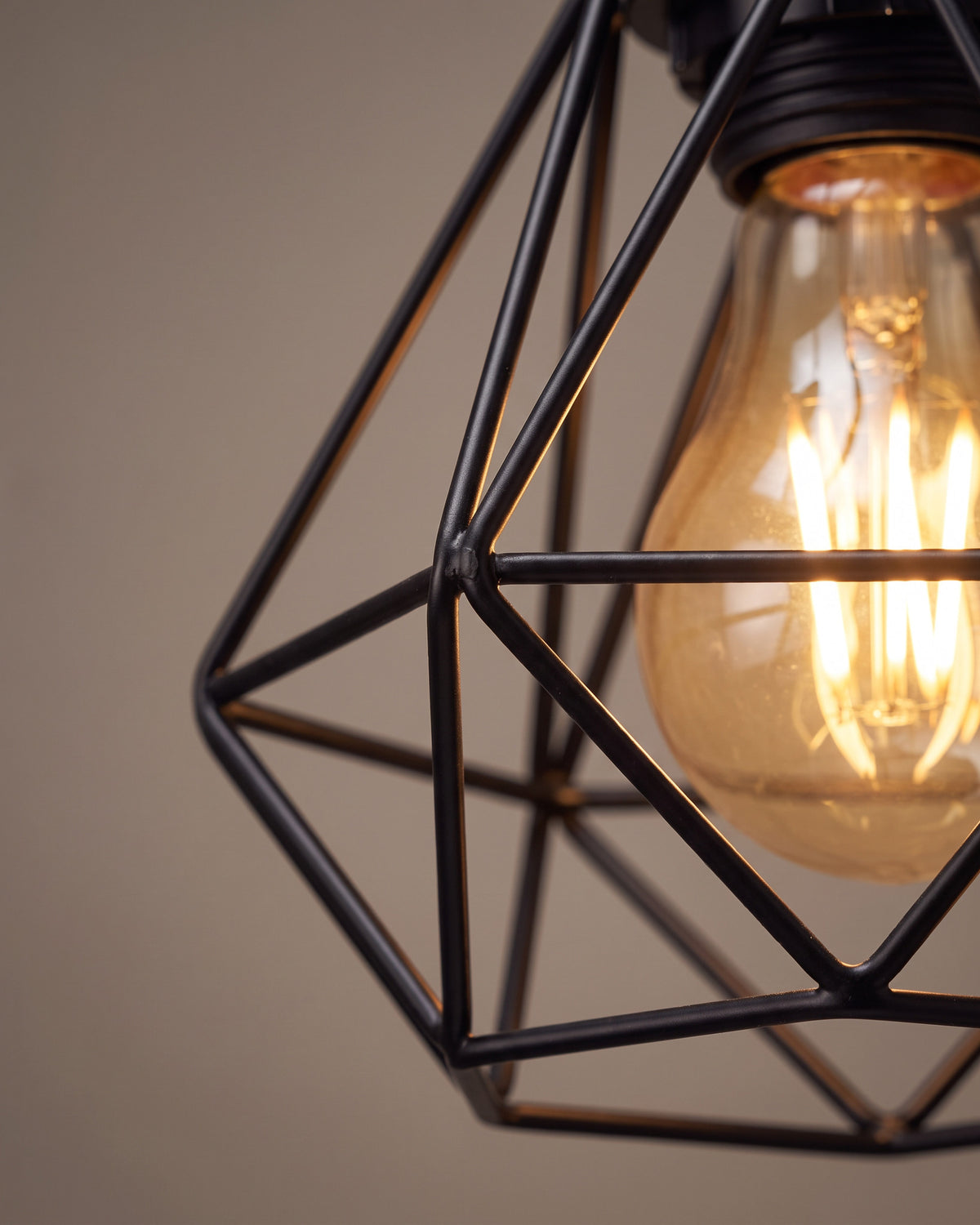 Suspension Volière : gros plan sur une cage diamant en fil noir avec l'ampoule à l'intérieur