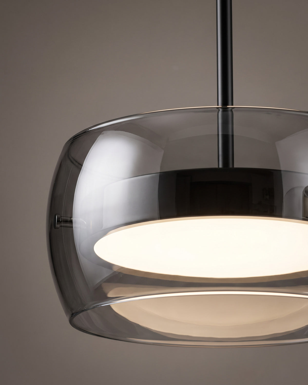 Suspension Trio : gros plan sur un tambour en verre fumé avec son disque lumineux et le bas de la tige