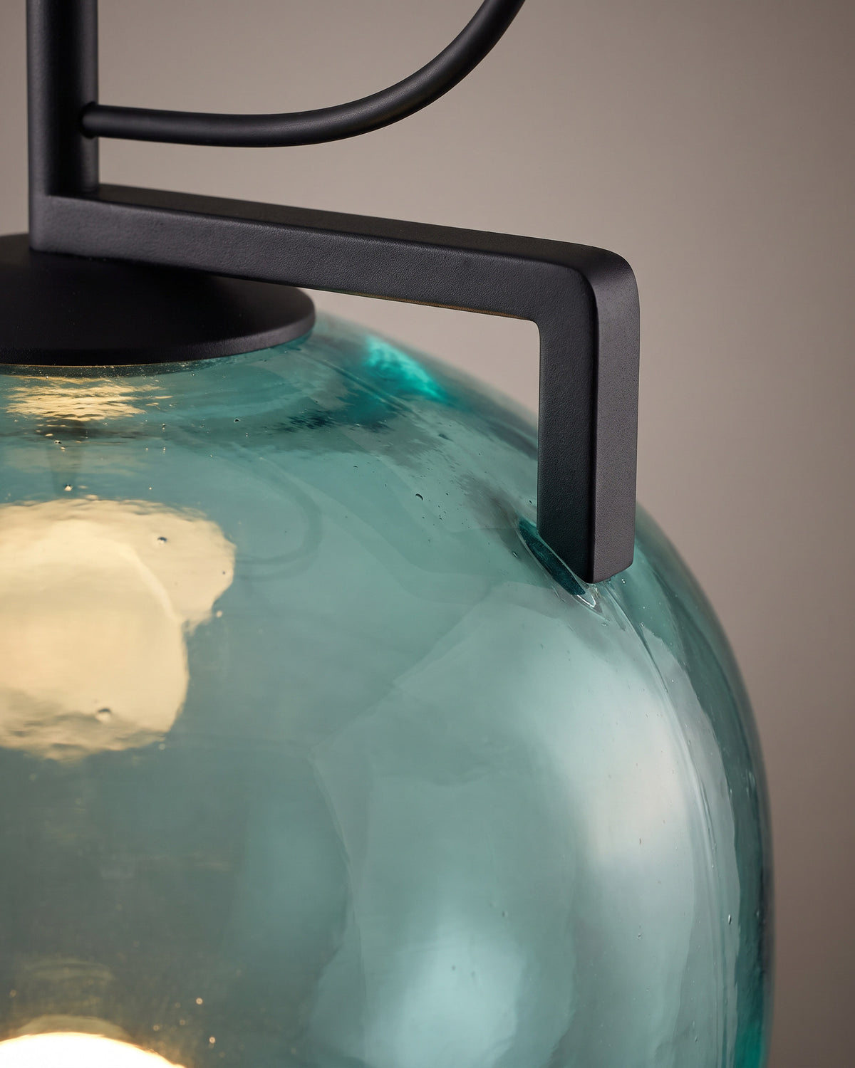 Suspension Lagon: gros plan sur le support coudé noir posé sur l'épaule du verre teinté